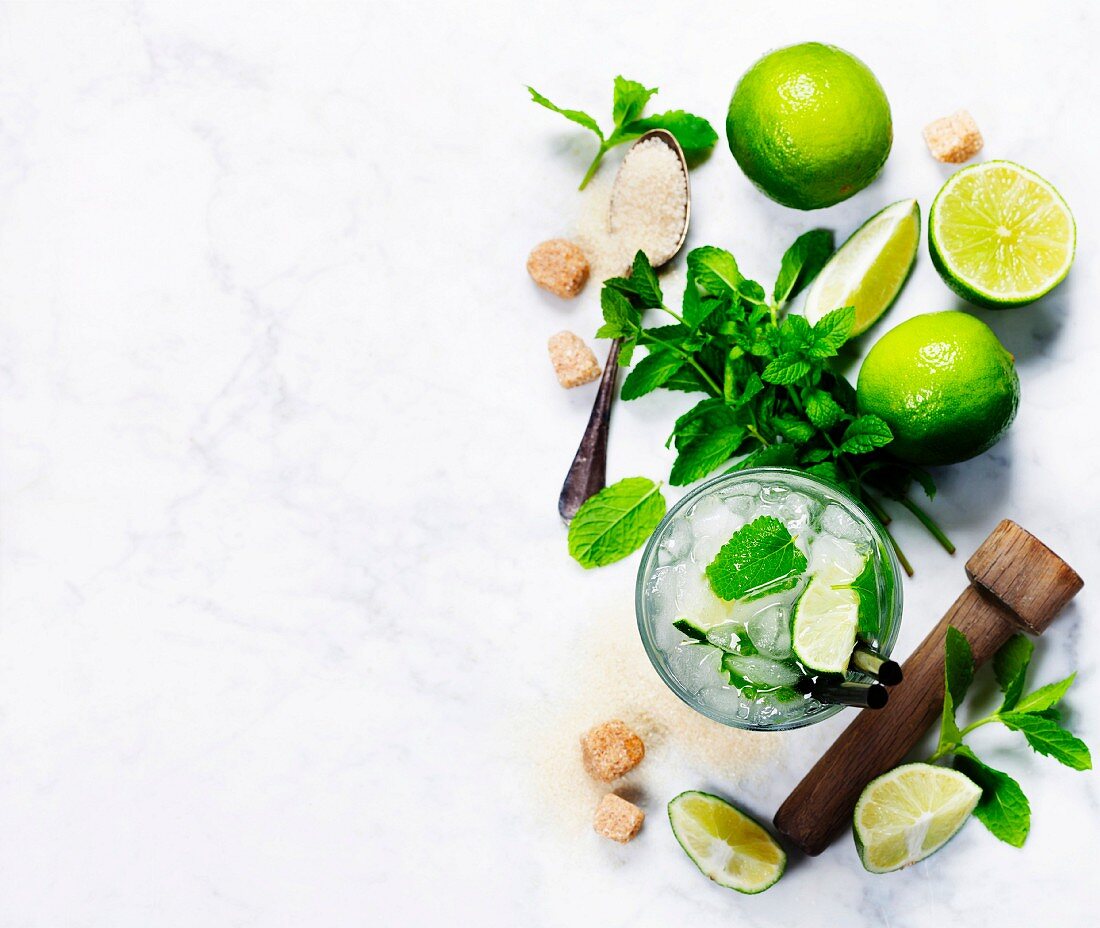 Ingredients for making mojitos (ice cubes, mint leaves, sugar and lime on rustic background)