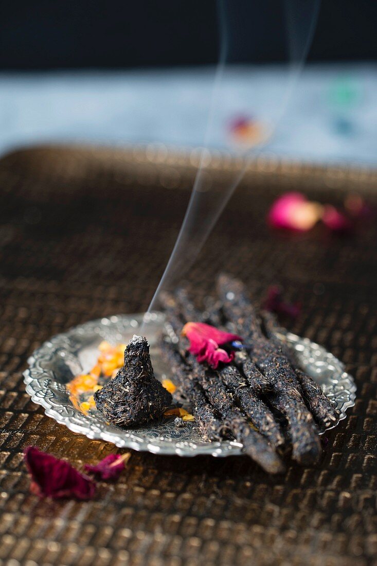 Homemade incense sticks and a cone made of charcoal, resin and dried herbs and flowers