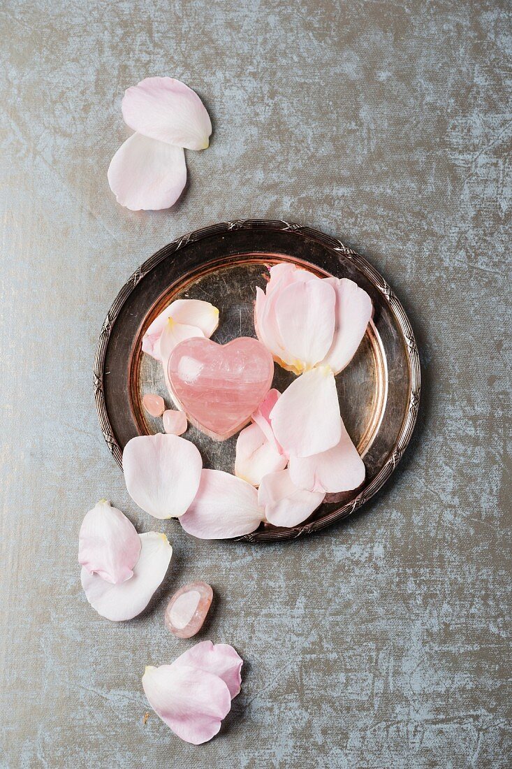 Rose quartz with rose petals on a silver plate