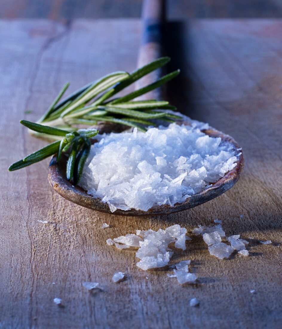 Sea salt flakes and rosemary on an old wooden spoon