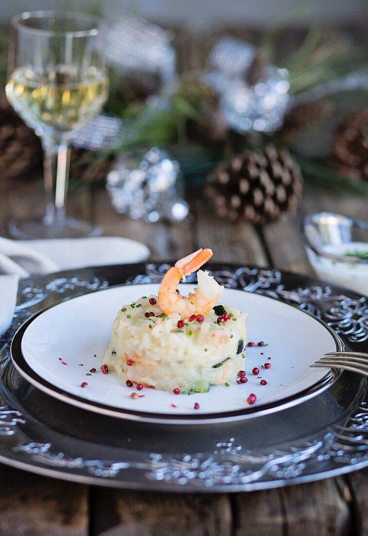 Shrimps and zucchini risotto on wooden table with christmas decorations