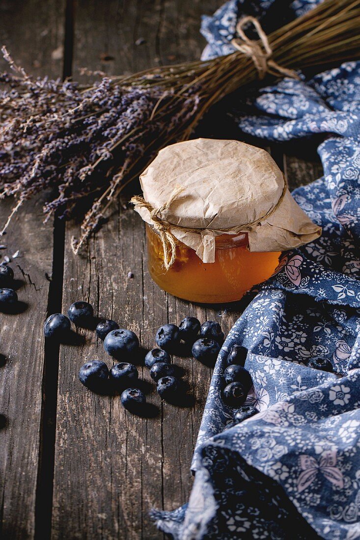 Stillleben mit Honiglas, frischen Heidelbeeren und getrocknetem Lavendel
