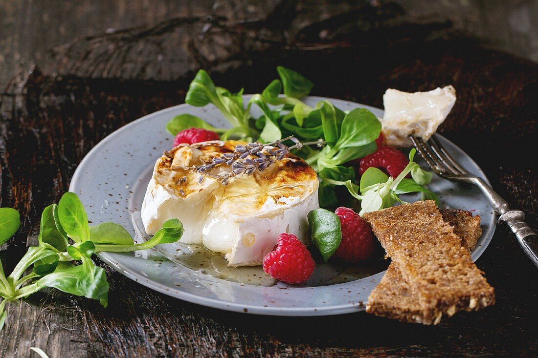 Melting sliced grilled goat cheese, served with liquid honey, lavender, raspberries, wholegrain toast and green salad