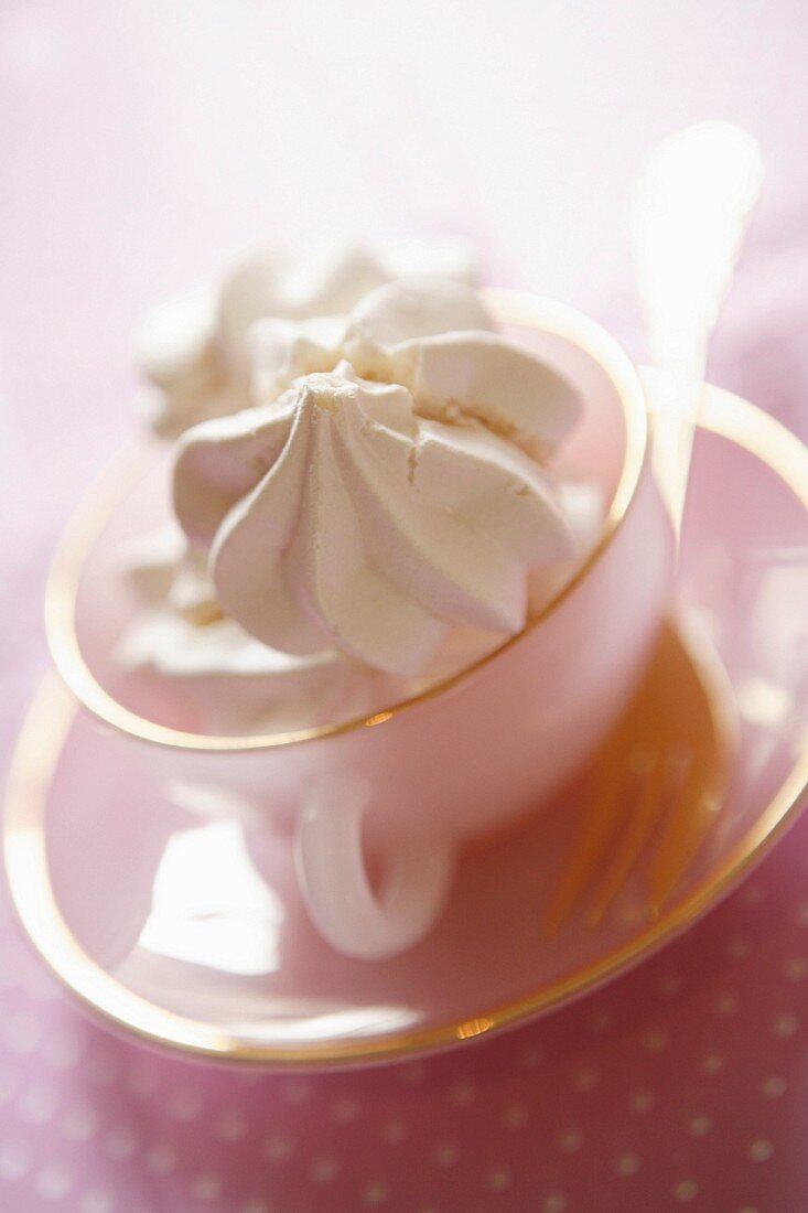 Meringue in a pink cup and saucer with fork