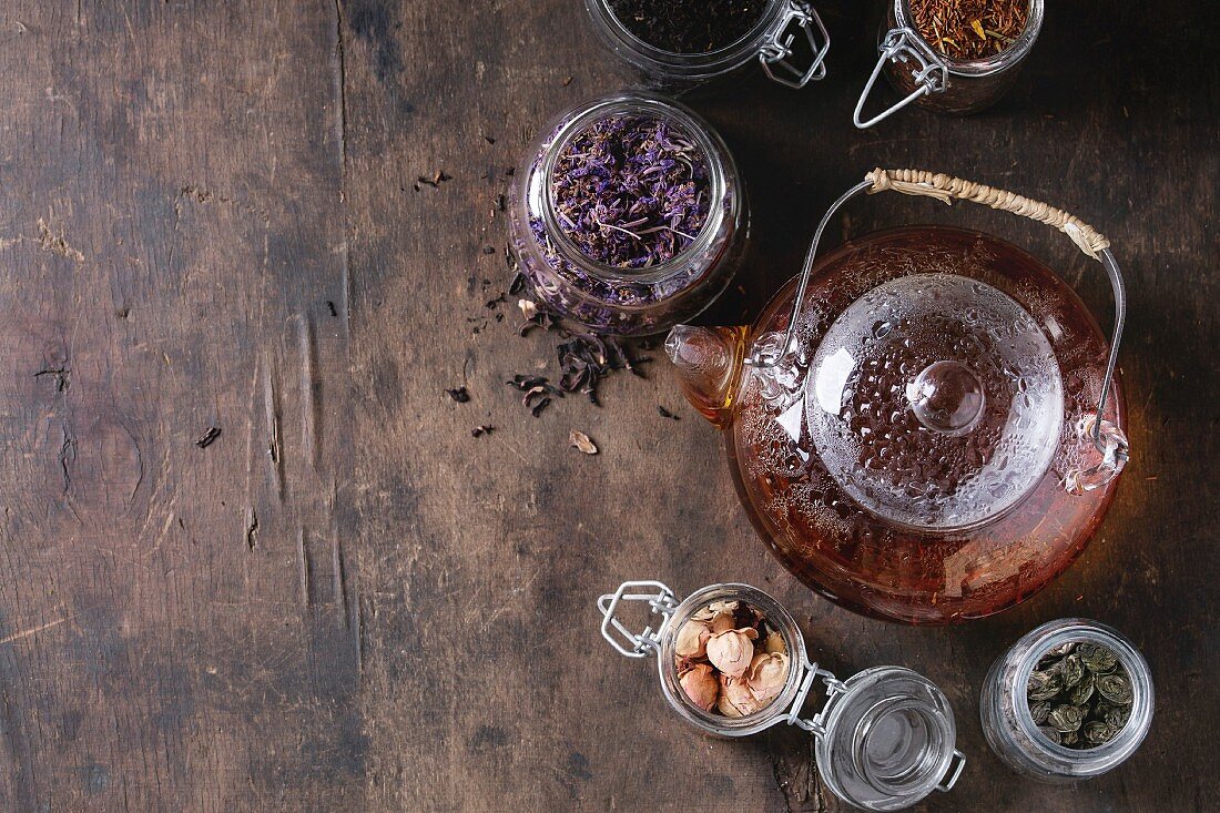 Stillleben mit verschiedenen Teesorten in Gläsern und Teekanne mit aufgebrühtem Tee
