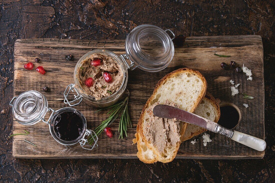 Glass jars of chicken liver pate with blackcurrant jam, pomegranate grain and sliced bread