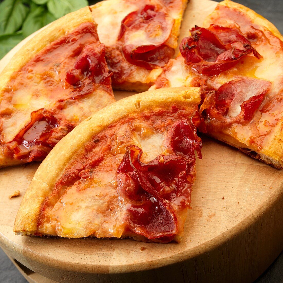 Pizzastücke mit Mozzarella, Schinken und Basilikum