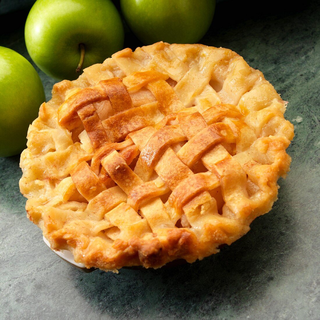 Ein kleiner gedeckter Apple Pie und grüne Äpfel