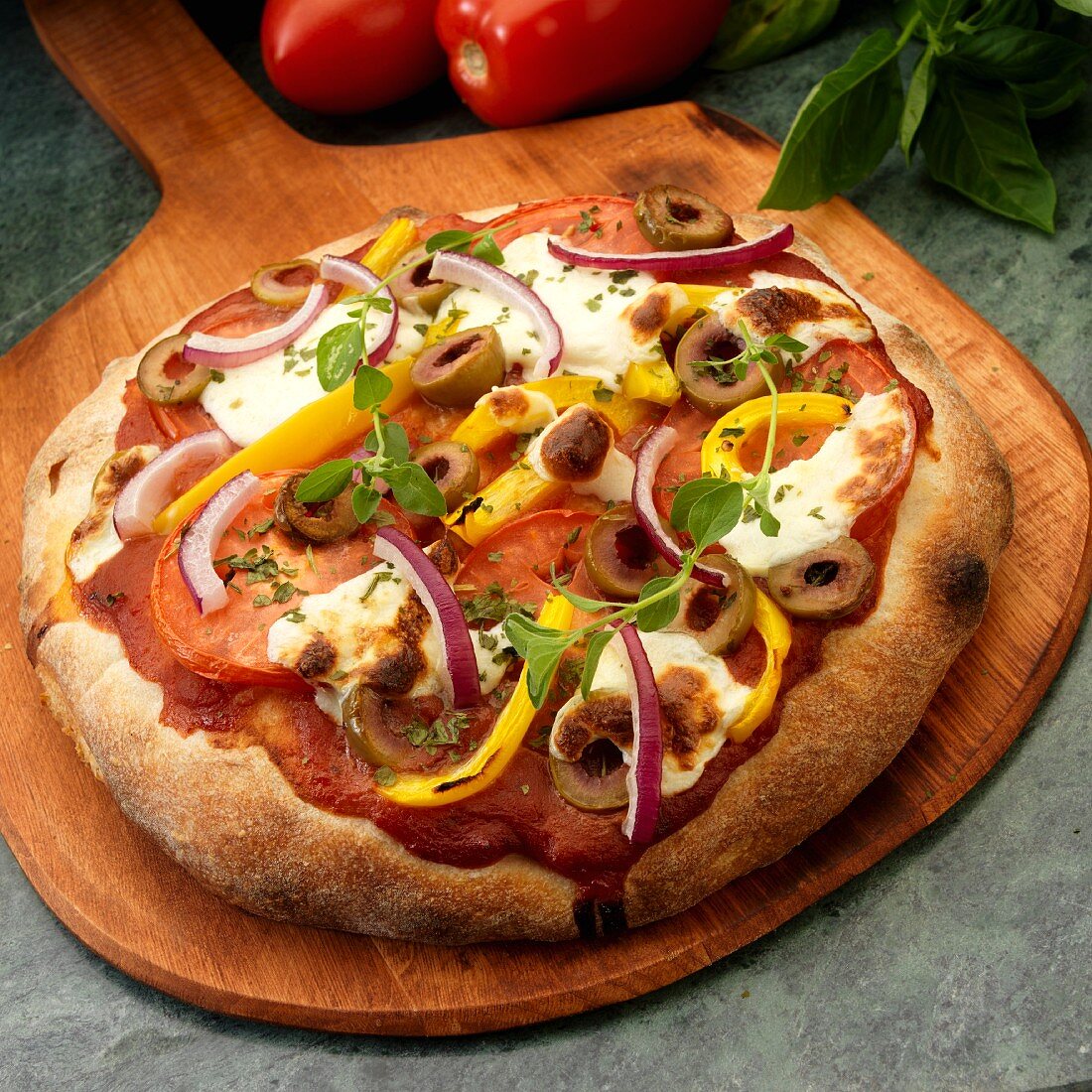 Rustic vegetarian Pizza with tomatoes, olives, yellow peppers, red onion, mozzarella