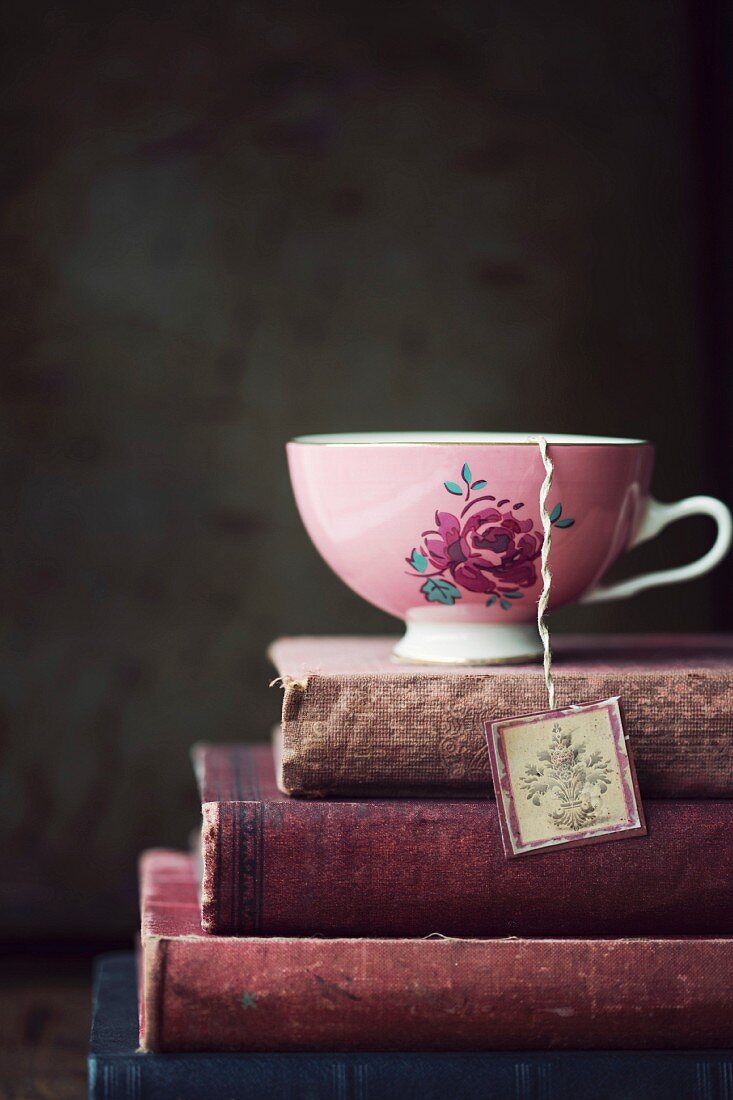 Vintage-Teetasse mit Blumenmotiv auf Stapel alter Bücher