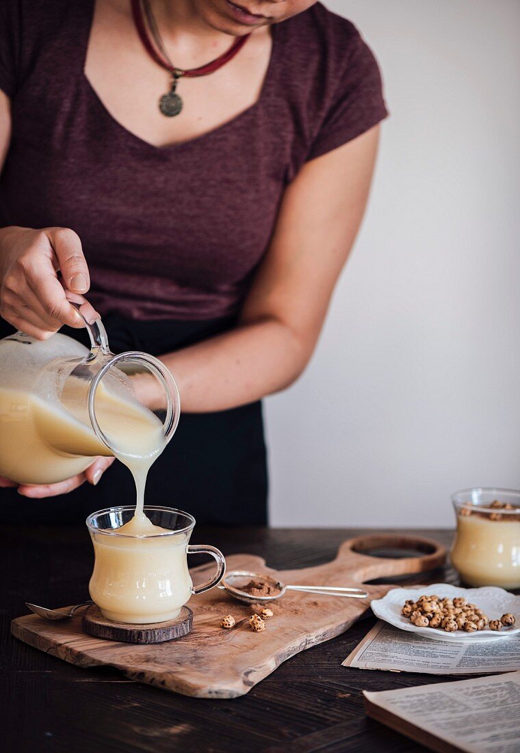 Frau giesst Boza (Biergetränk, Türkei) aus Krug in Glas