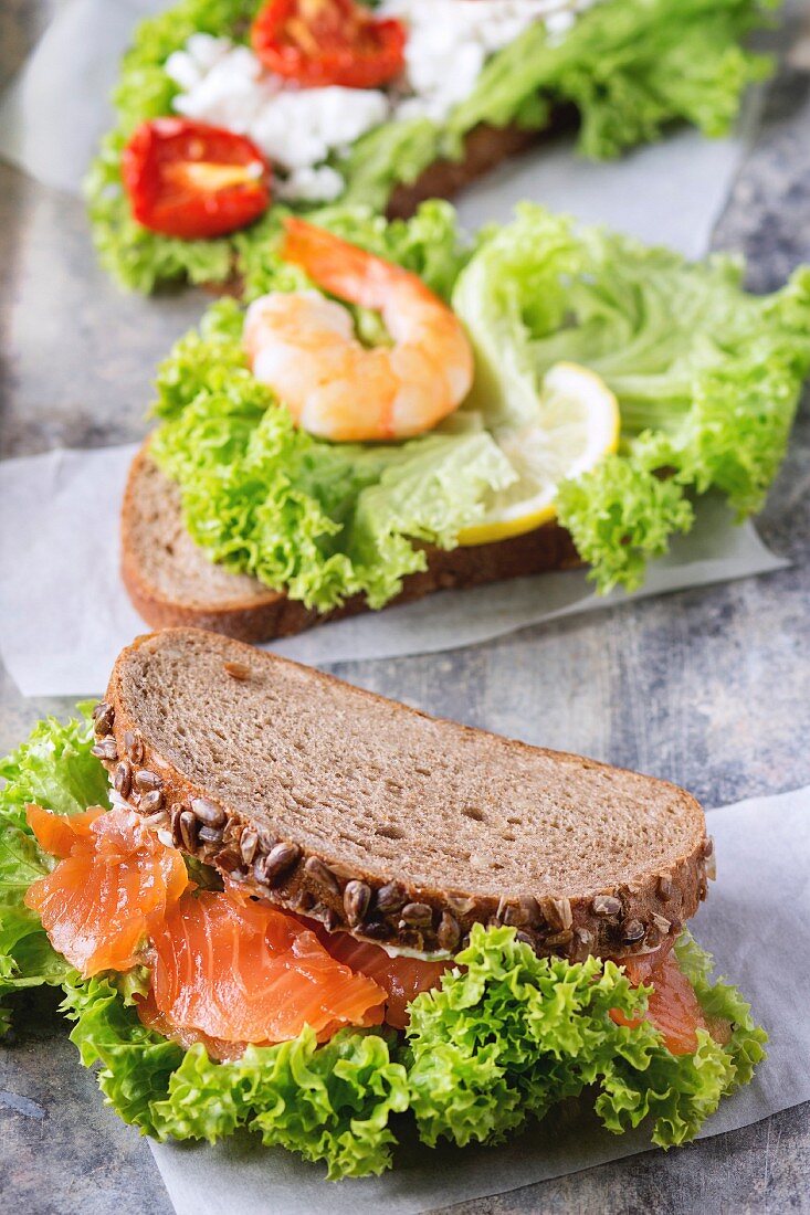 Set of Sandwiches with whole wheat bread, fresh salad, feta cheese, cherry tomatoes, shrimp and salted salmon