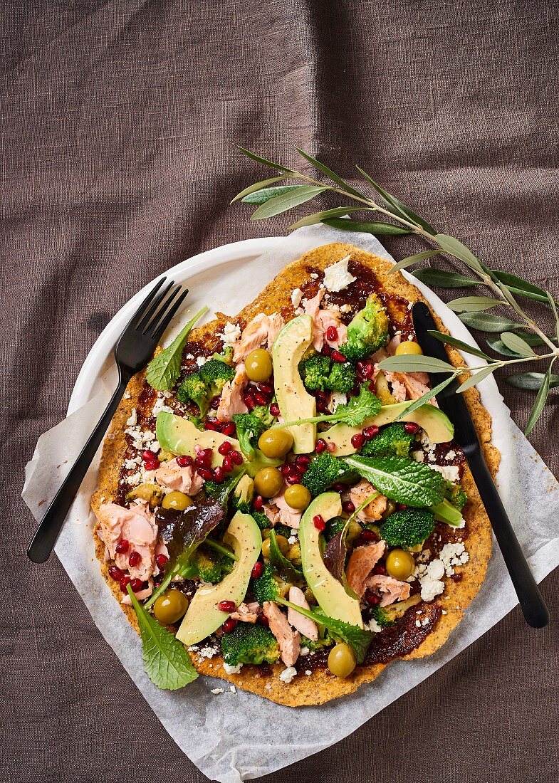 Chickpea pizza with trout fillets, avocado, pomegranate and feta