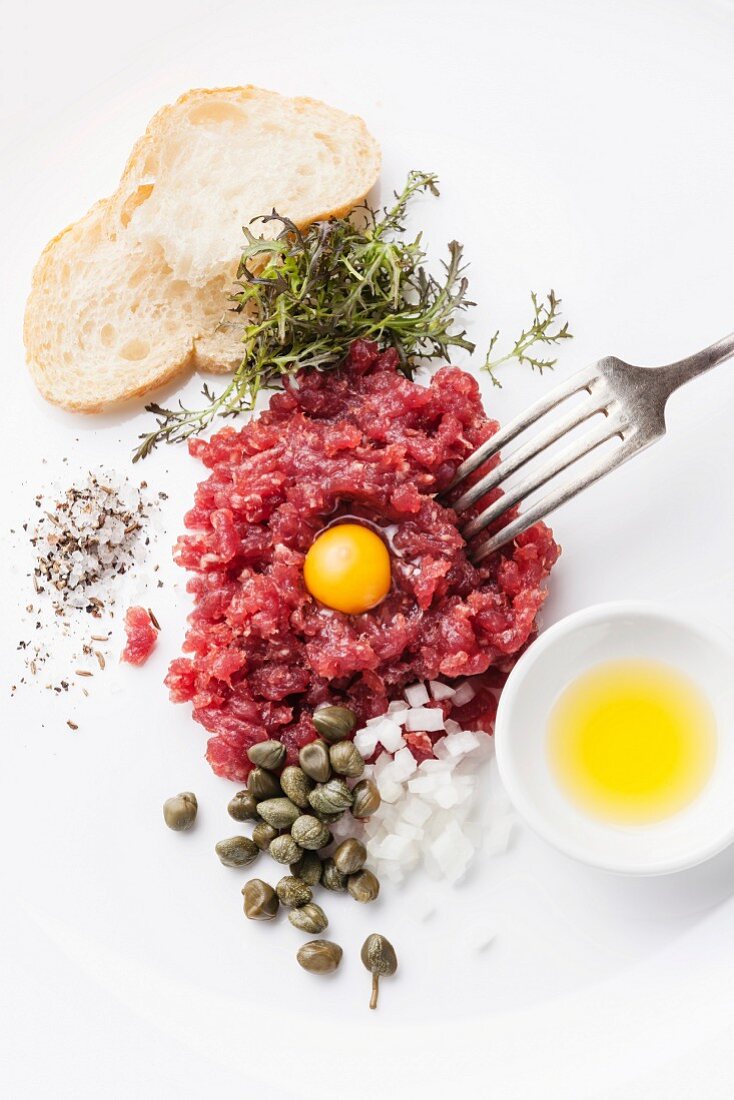 Beef tartare with capers and fresh onions on white background