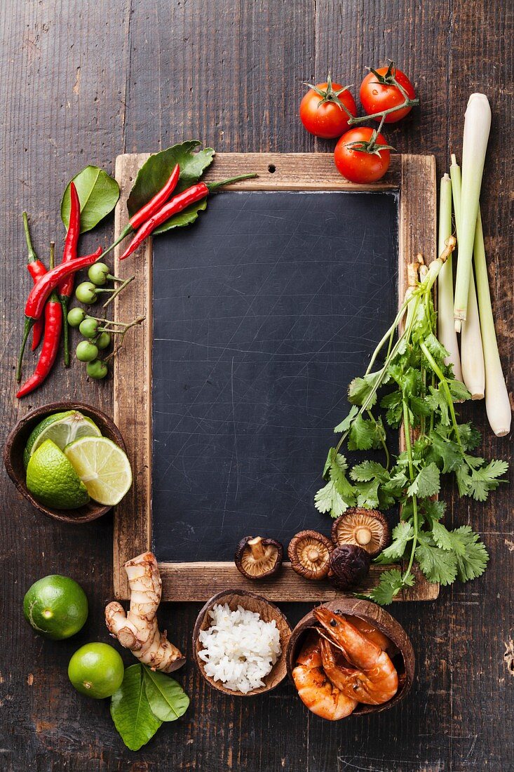 Ingredients for spicy Thai soup Tom Yam with Coconut milk, Chili pepper and Seafood on vintage slate chalk board