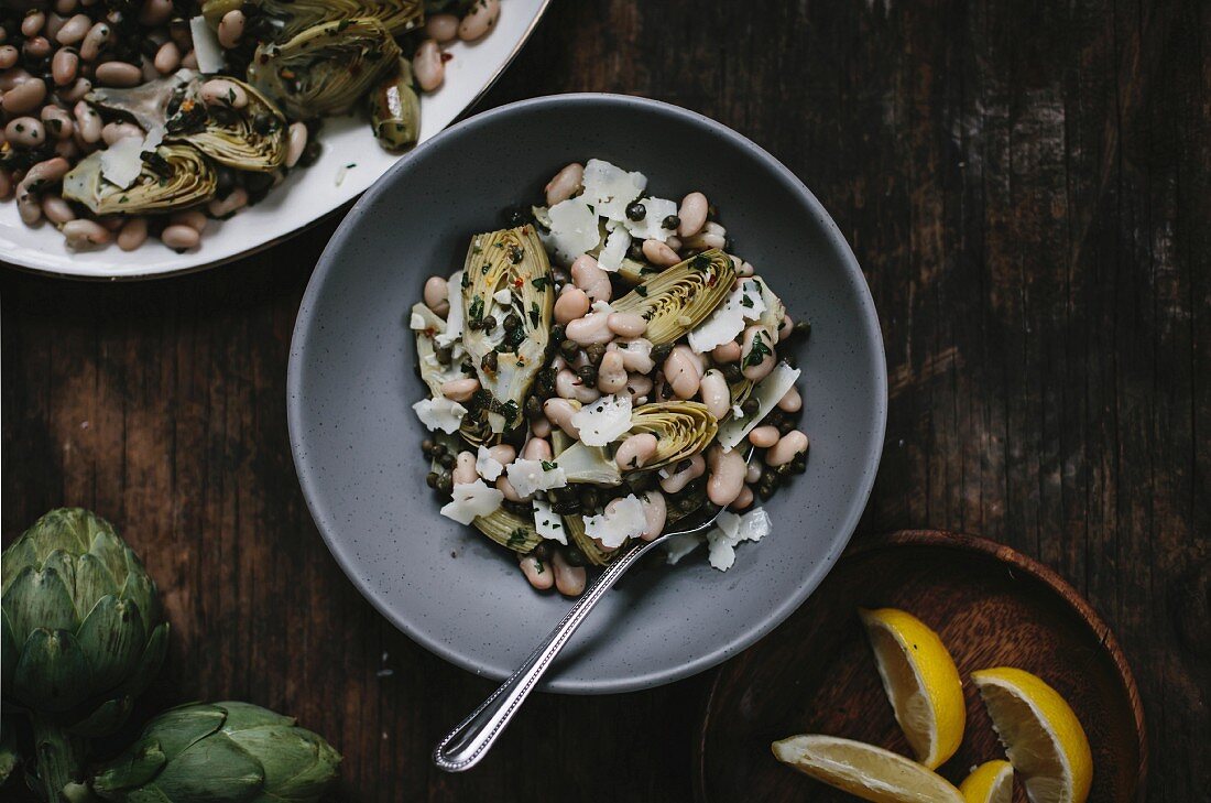 A bowl of braised baby artichoke salad with white beans and shaved manchego