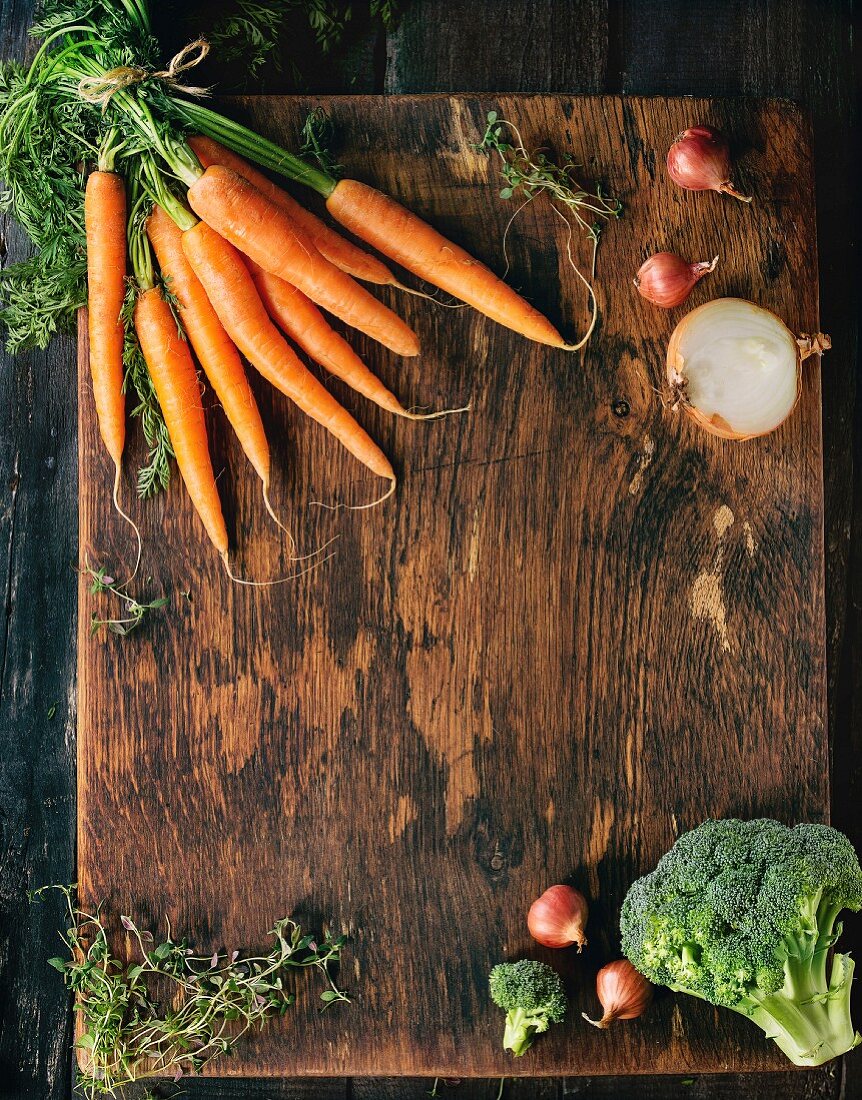 Wooden healthy food background with raw vegetables and herbs (carrots, onions, broccoli and thyme)