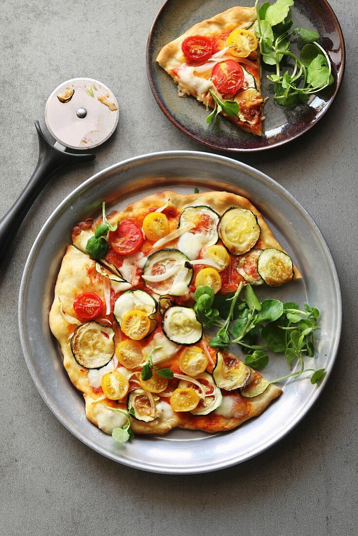 Vegetarische Pizza mit Zucchini, Zwiebeln, Tomaten, Kresse und Mozzarella