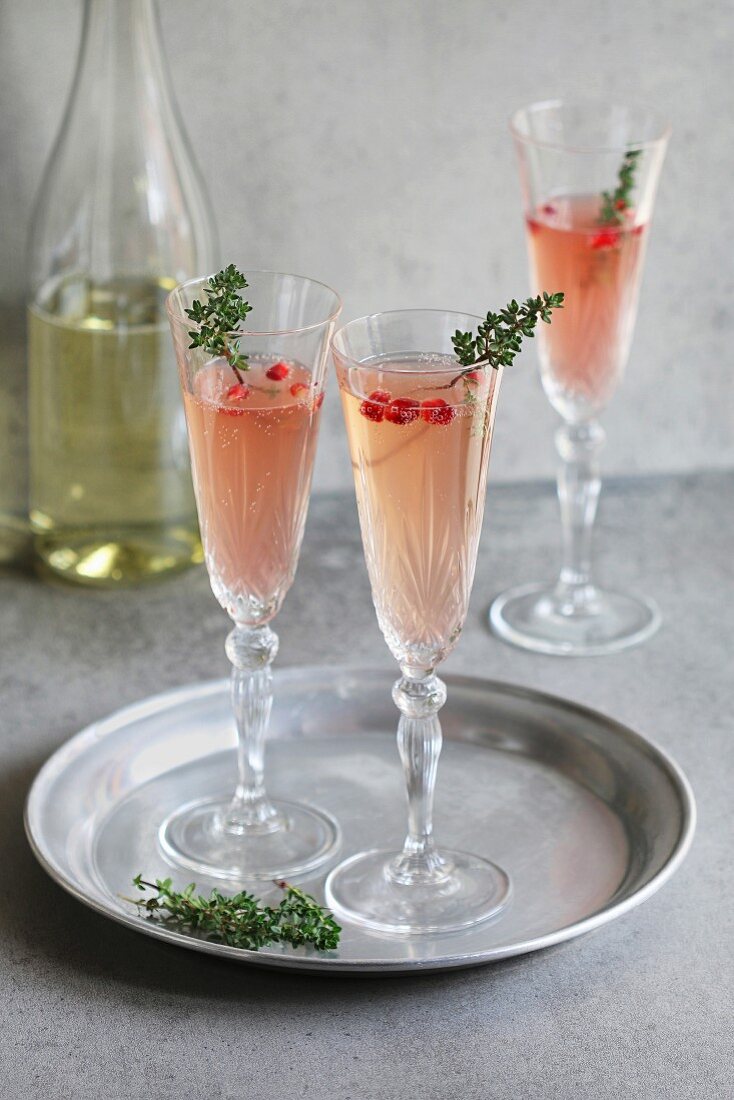 Pomegranate champagne in glasses with fresh thyme decoration