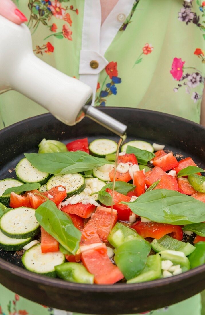 Mixed vegetables in a pan, having olive oil poured over them
