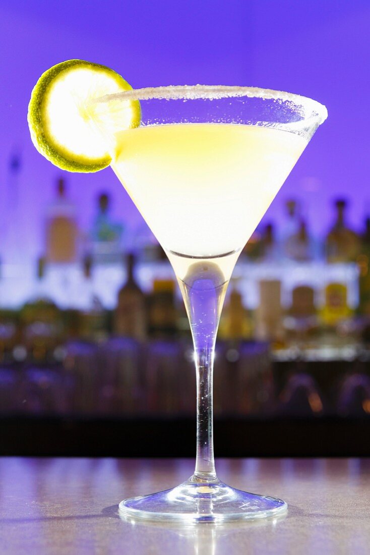 Ein Cocktail mit Limette im Glas auf Bartheke in Cocktailbar