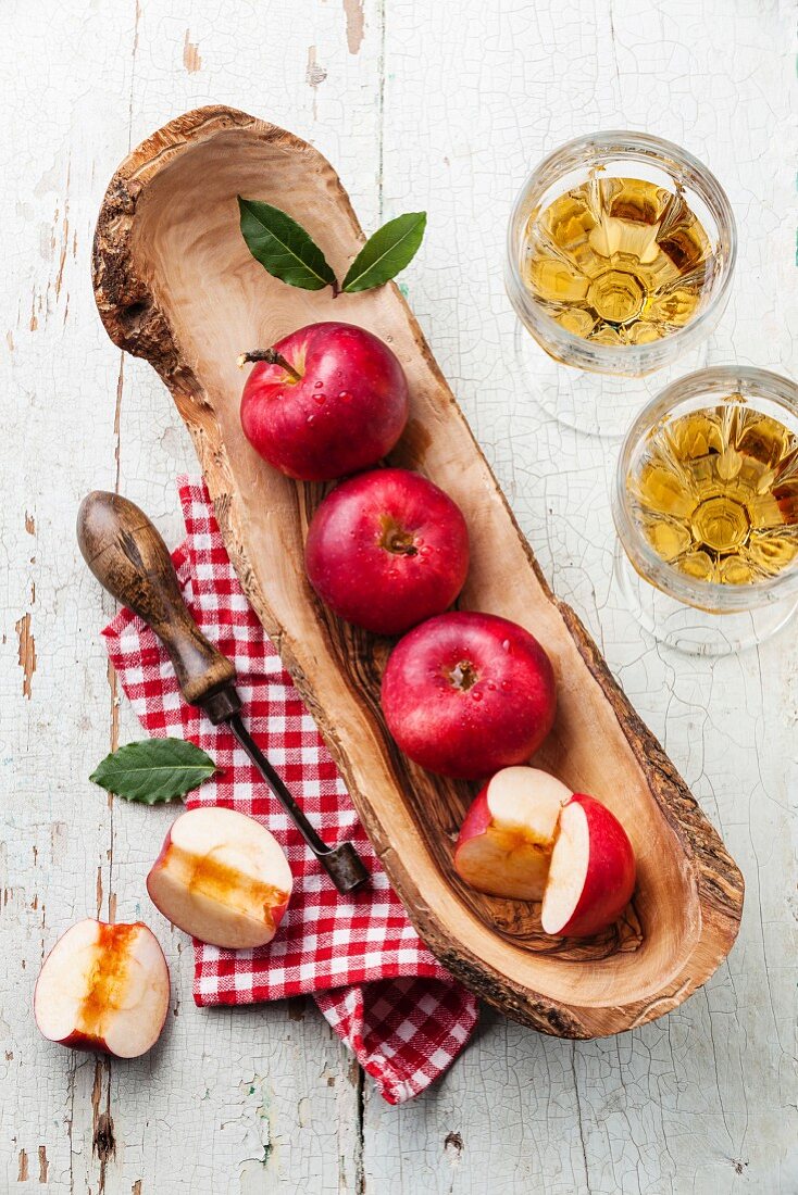 Rote reife Äpfel in Olivenholz-Schüssel und Vintage Entkerner