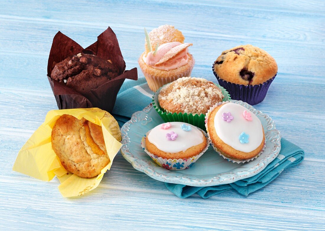 Verschiedene Cupcakes und Muffins auf blauem Holzuntergrund