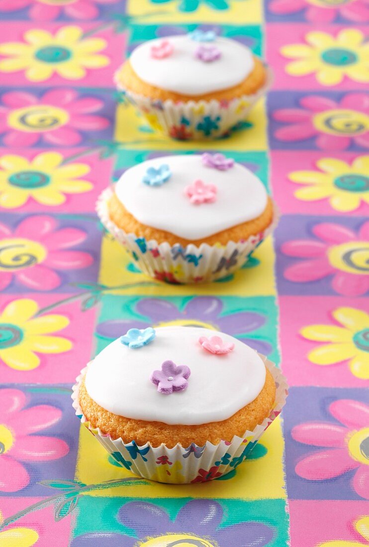 Drei Fairy Cakes mit Zuckerglasur und Zuckerblüten