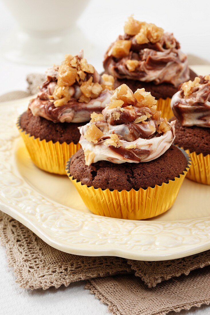 Several Peanut butter and chocolate cupcakes with chocolate and cream cheese topping and peanut brittle chips
