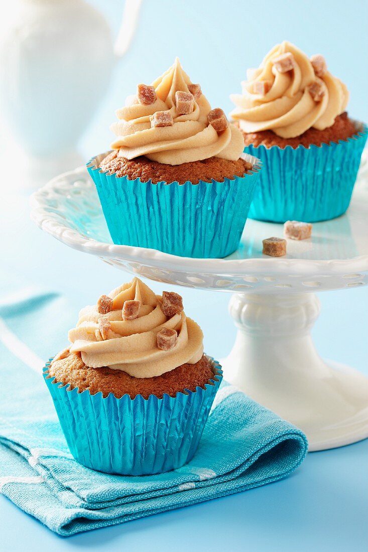 Sticky toffee cupcakes with caramel icing and fudge pieces in blue metalic cupcake cases