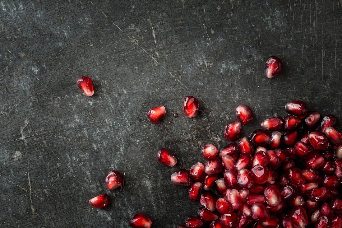 Pomegranate seeds on a grey metal surface