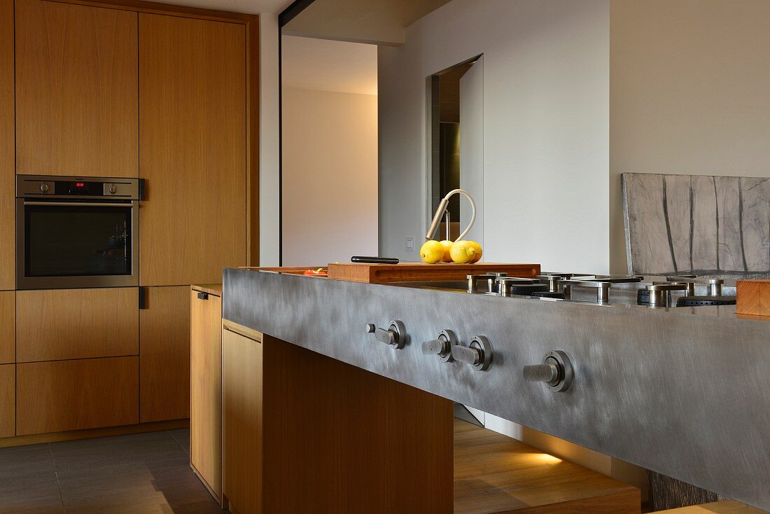 Metal kitchen counter with gas cooker and fitted cupboards next to open doorway