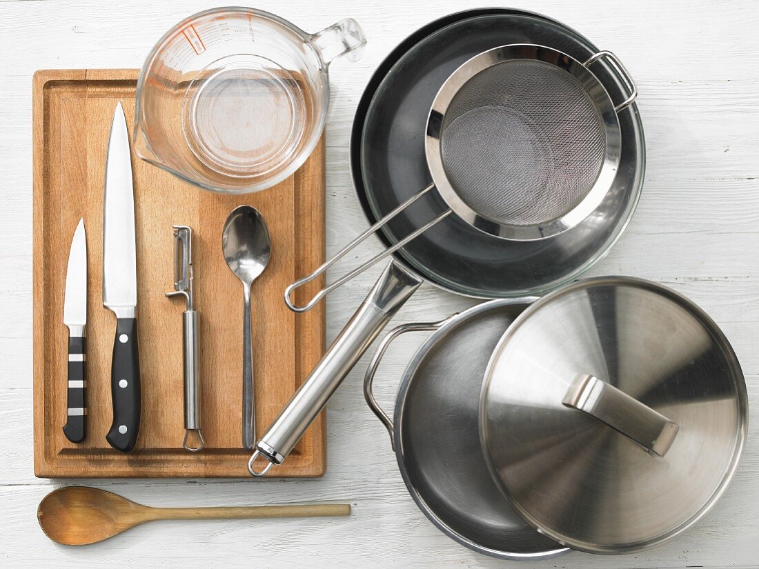 Various kitchen utensils: pot, pan, sieve, measuring cup, knife, vegetable peeler