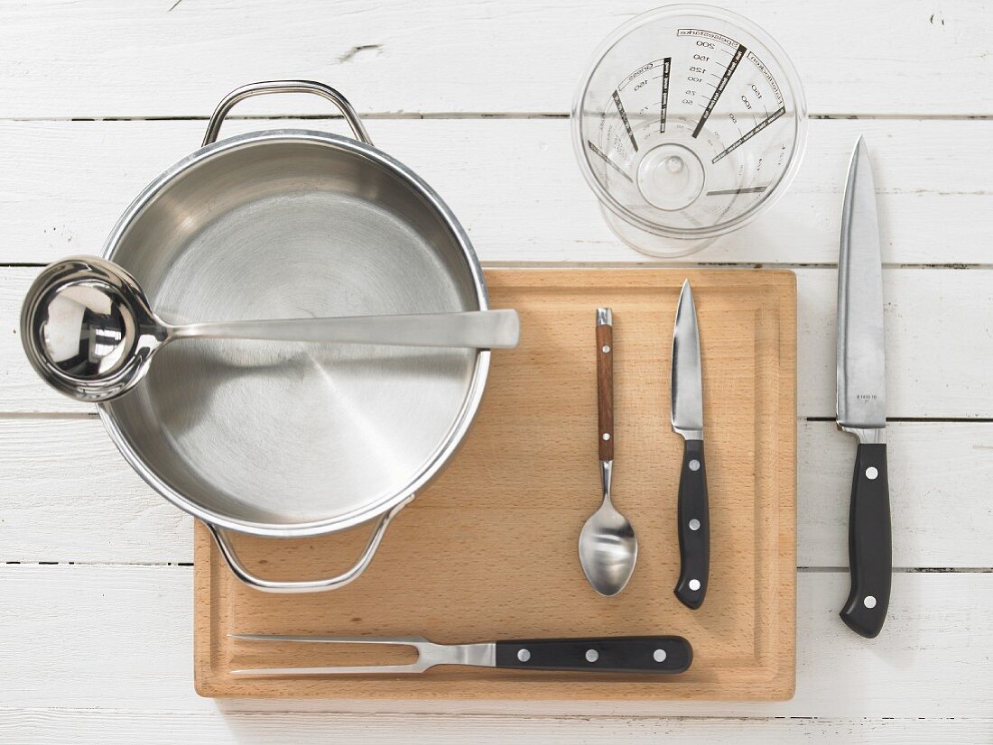 Various kitchen utensils: pot, ladle, measuring cup, meat fork, knife