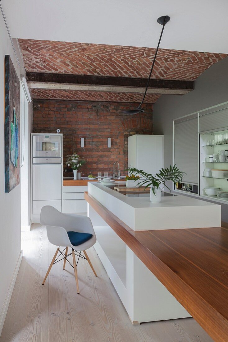 Brick wall and vaulted ceiling in kitchen with white glossy cabinets