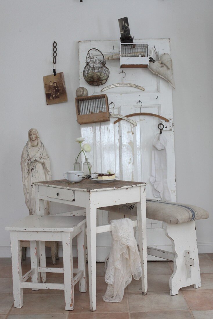 Shabby-chic seating area in front of old door leant against wall