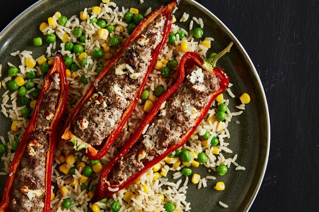 Red pointed pepper filled with minced beef and quark on a bed of rice with sweetcorn and peas