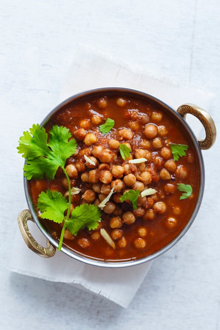 Chickpeas soaking in a bed of onion tomato sauce, garnished with coriander leaves and ginger juliennes