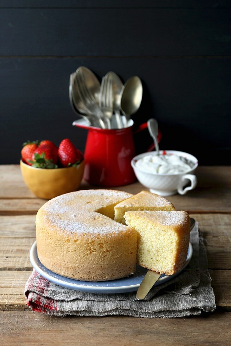 Frisch gebackener Biskuitkuchen mit Sahne und Erdbeeren, angeschnitten