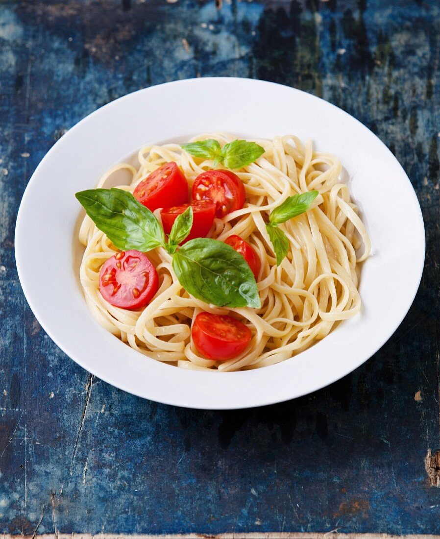 Spaghetti with tomato and basil on blue wooden background