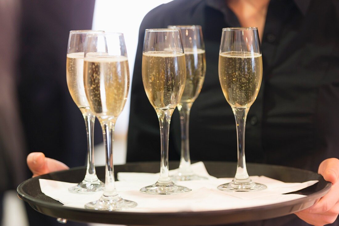 Kellnerin serviert Champagner in Gläsern auf Tablett