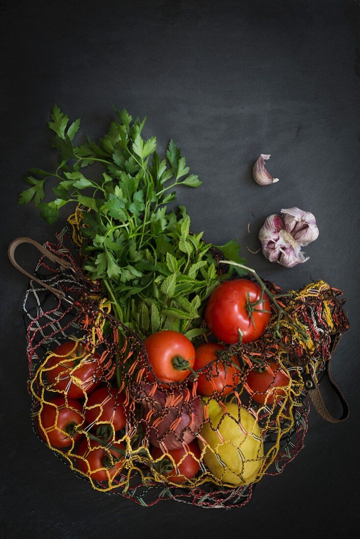 Frisches Gemüse vom Markt im Einkaufsnetz auf Schieferuntergrund