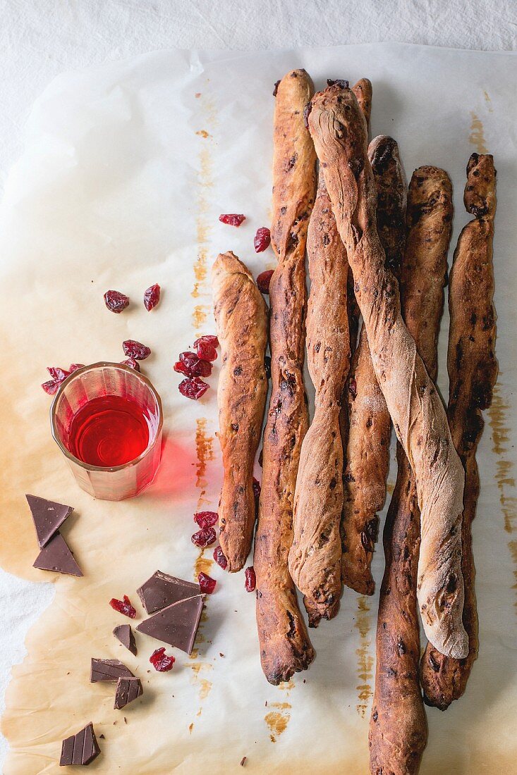 Fresh baked homemade sweet chocolate grissini bread sticks over baking paper with glass of red berry liqueur