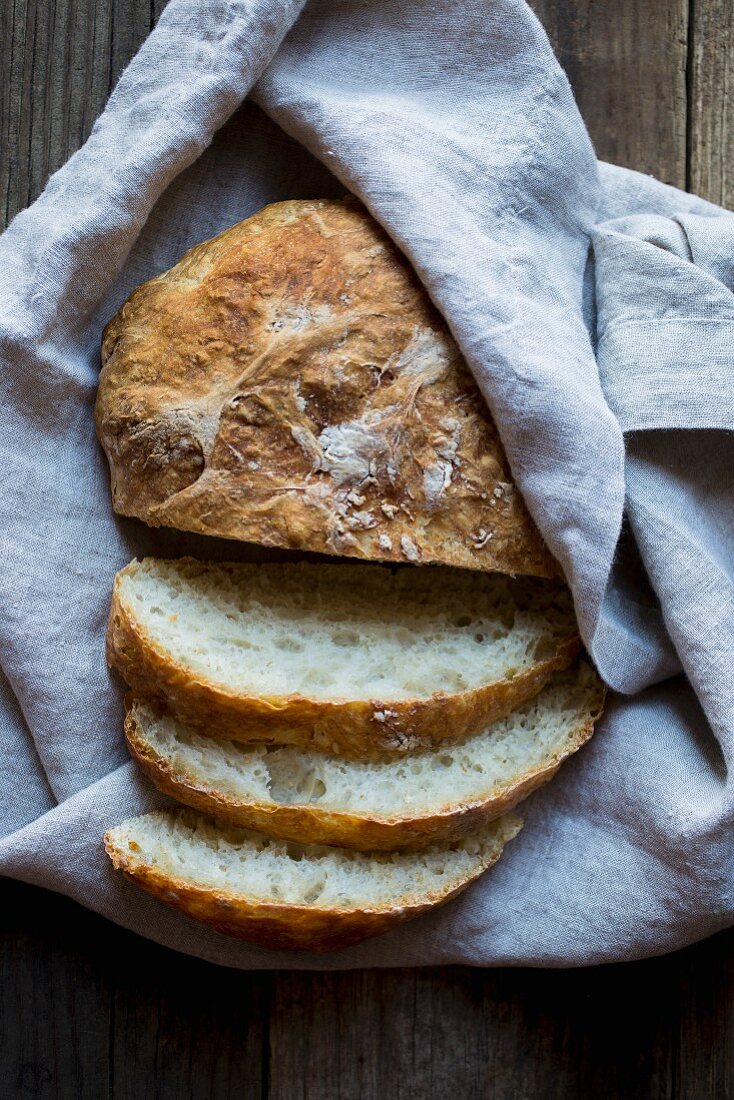 Brot, teilweise in Scheiben geschnitten, in Leinentuch gewickelt