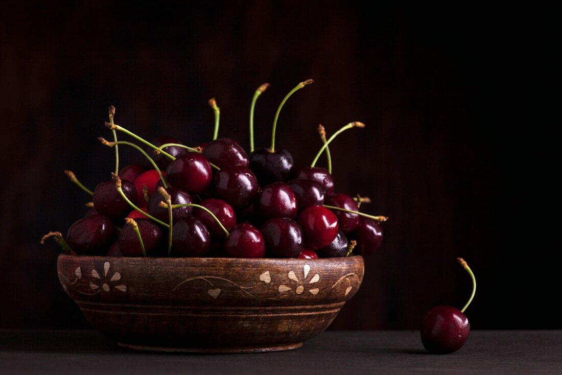 Fresh cherries in bowl on wooden table