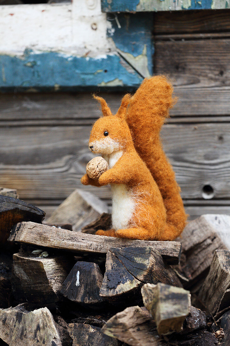 Hand-made, felted, woollen squirrel on firewood