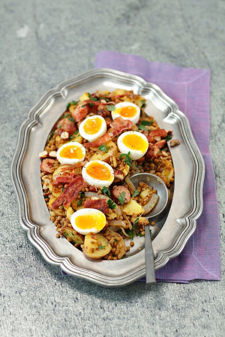 Brown lentil, potatoes and sausage salad with bacon and eggs