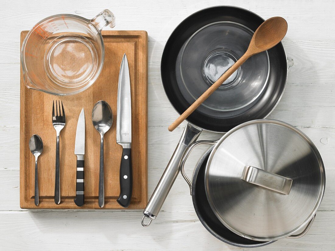 Various kitchen utensils: pot, pan, measuring cup, knives, spoons