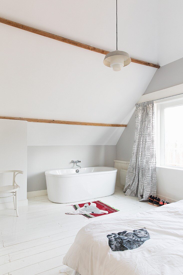 Free-standing bathtub under sloping bathroom ceiling