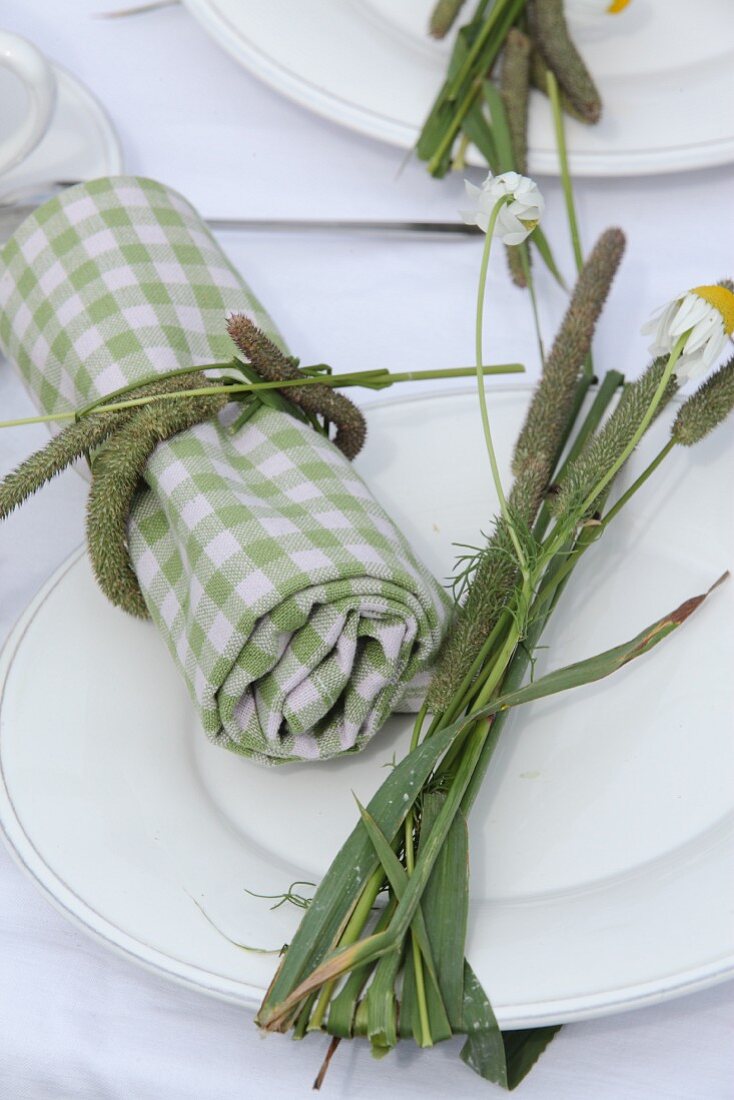 Grün-weiss karierte Stoffserviette mit Grashalm umwickelnt